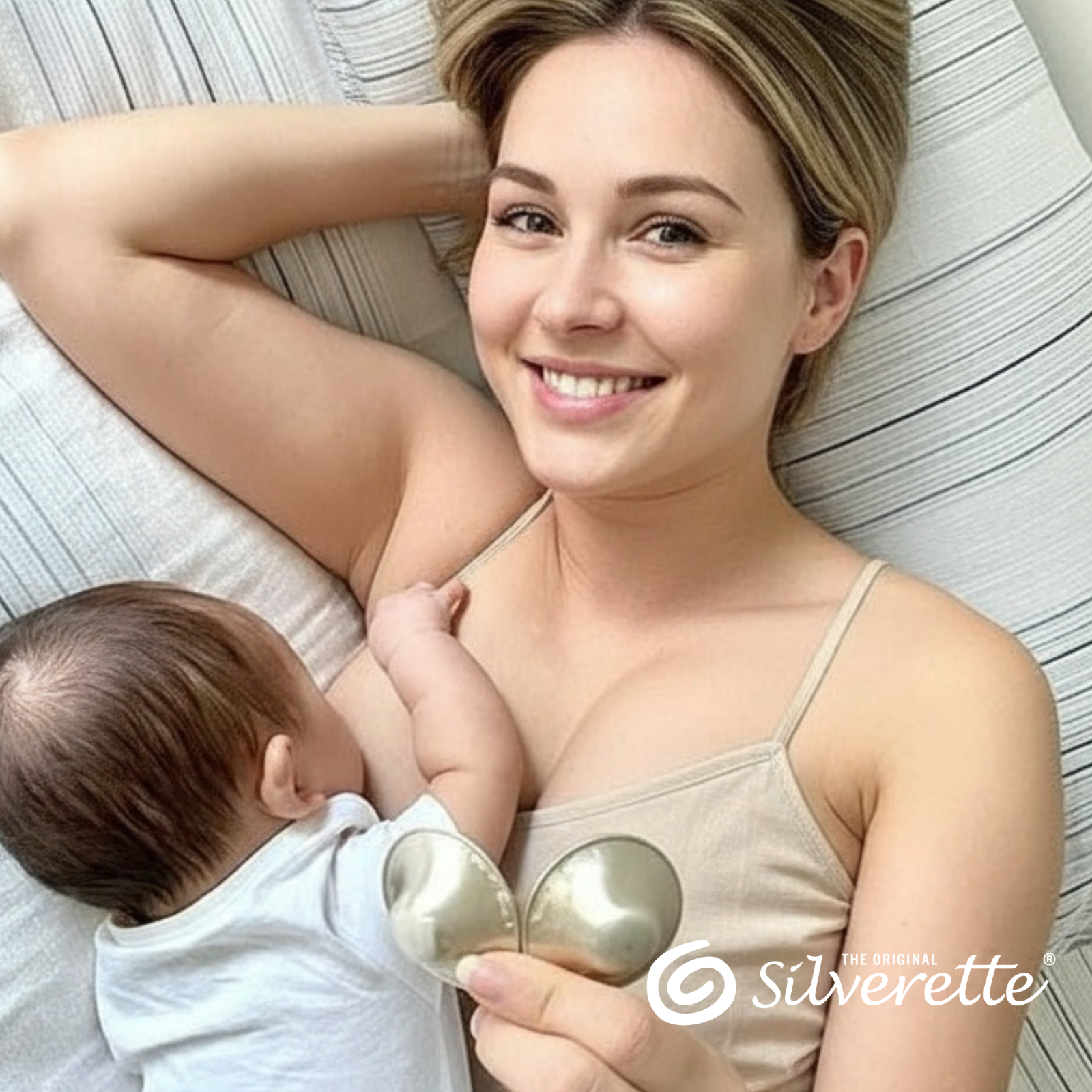 Smiling mother lying with her baby while wearing Silverette sterling silver nursing cups