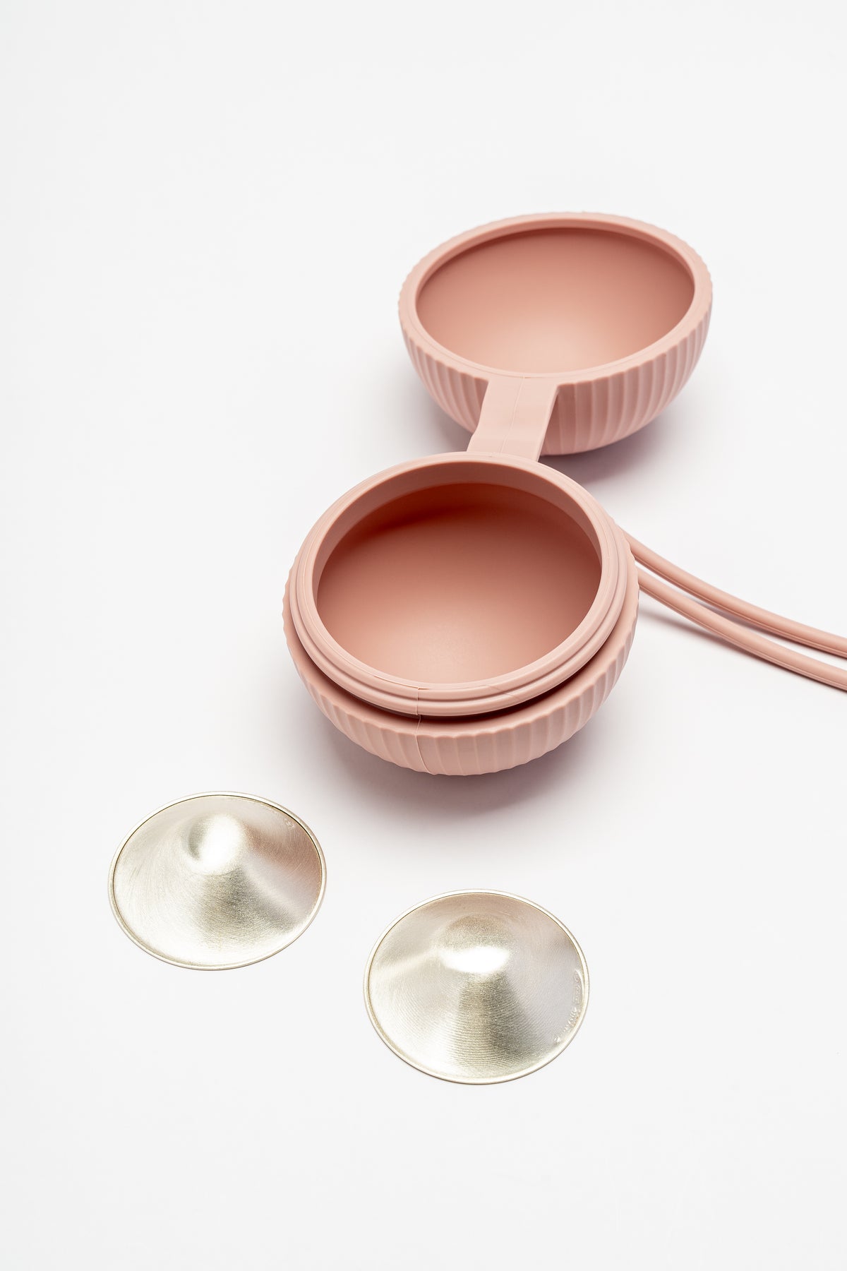 Pink silicone cup holder shown open beside a pair of Silverette 925 silver nursing cups