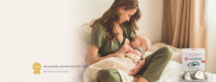 Mother breastfeeding her baby on a bed beside a box of Silverette 925 sterling silver nursing cups, with the Bounty Baby Awards Gold badge